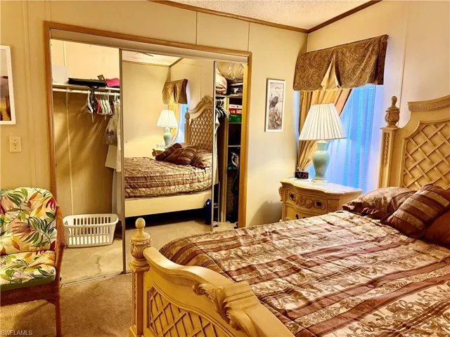 Bedroom with ornamental molding, a closet, light carpet, and a textured ceiling