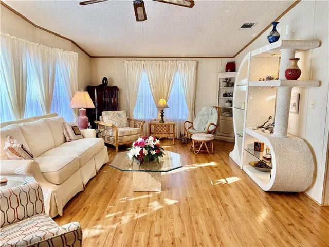 Living area with ornamental molding, a ceiling fan, hardwood / wood-style floors, a textured ceiling, and healthy amount of natural light