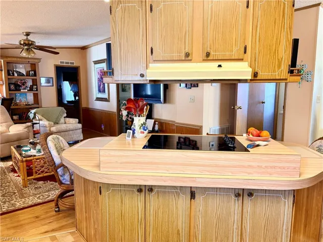Kitchen featuring crown molding, wainscoting, a ceiling fan, open floor plan, and light countertops