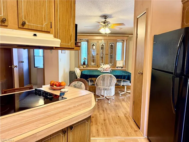 Kitchen with black appliances, a textured ceiling, a ceiling fan, wood finish cabinetry, and plenty of natural light