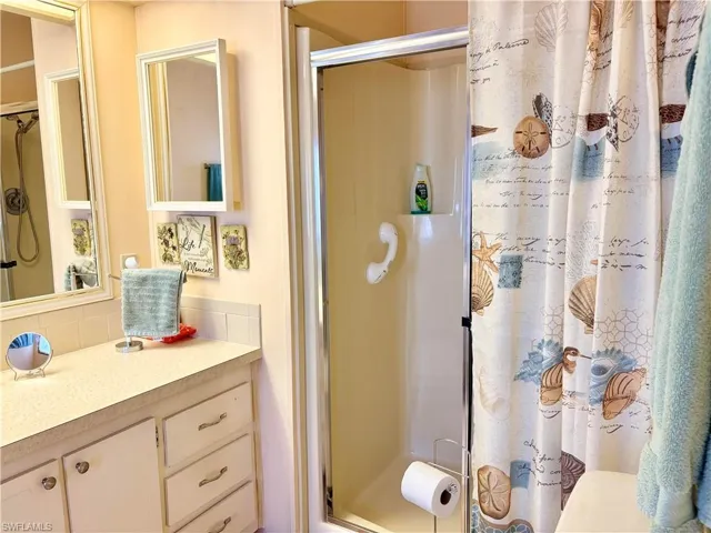 Full bath featuring a shower stall, vanity, and backsplash