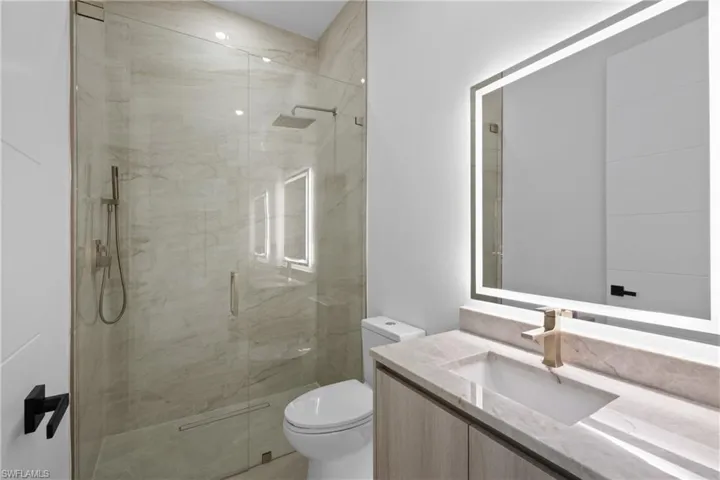 Bathroom with vanity and a marble finish shower