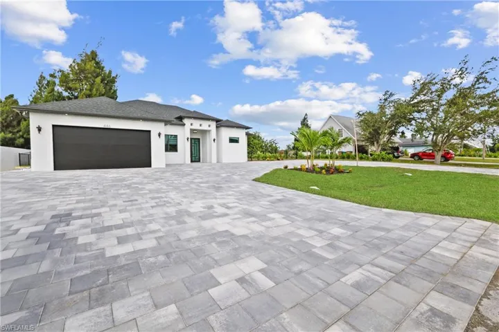 View of front of house featuring decorative driveway, a garage, a front yard, and stucco siding