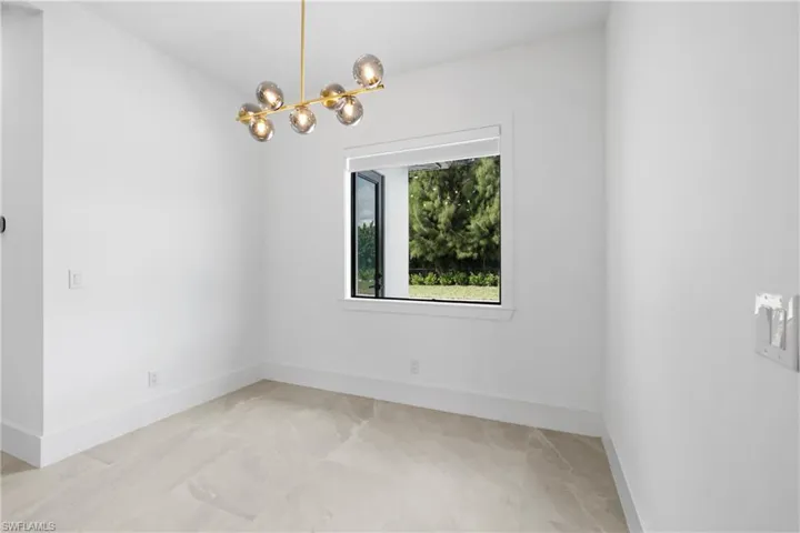 Empty room with baseboards and a chandelier