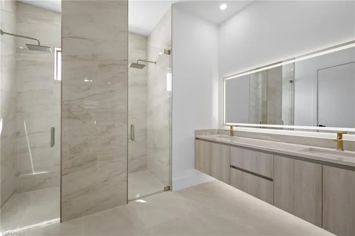 Bathroom with double vanity and a marble finish shower