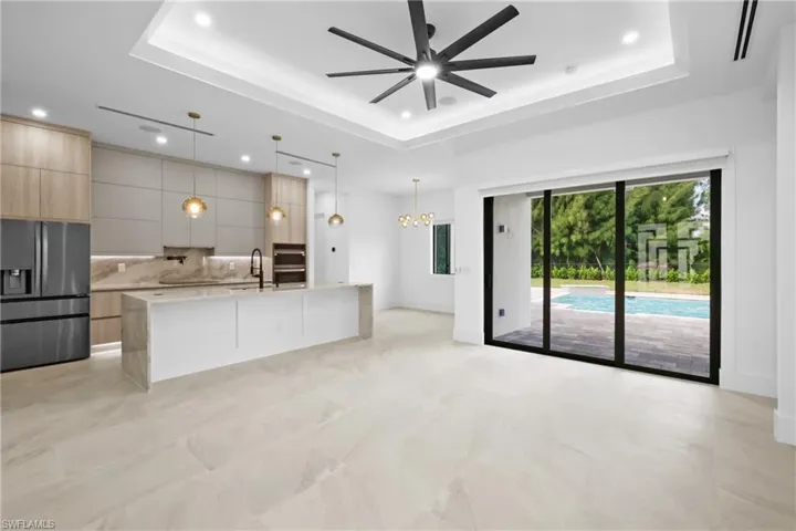 Unfurnished living room featuring a tray ceiling, recessed lighting, a chandelier, and a ceiling fan