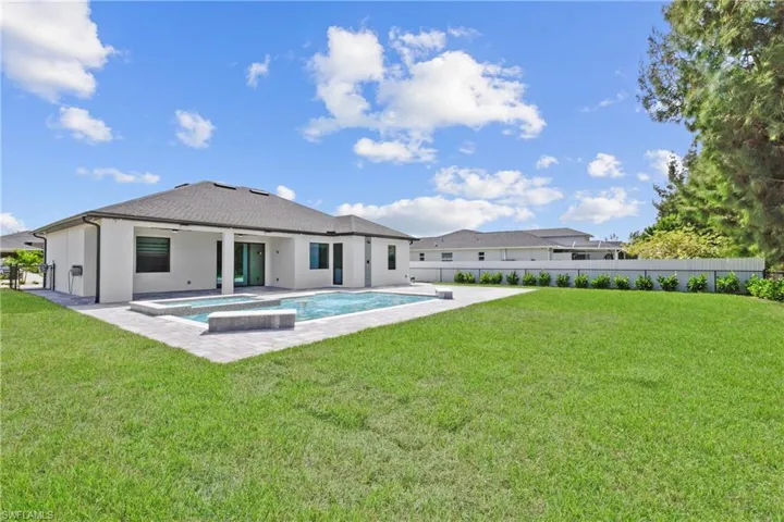 Back of property featuring a patio, stucco siding, a pool with connected hot tub, ceiling fan, and a fenced backyard