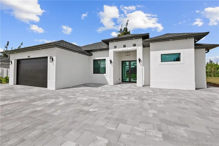 Prairie-style house with french doors, stucco siding, a garage, and decorative driveway