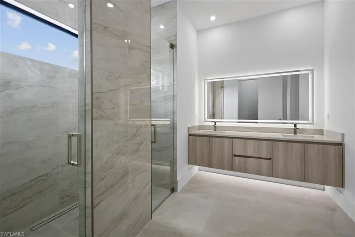 Bathroom with double vanity, a marble finish shower, and recessed lighting