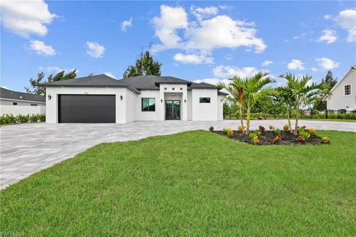 View of front of home with decorative driveway, stucco siding, an attached garage, and a front lawn