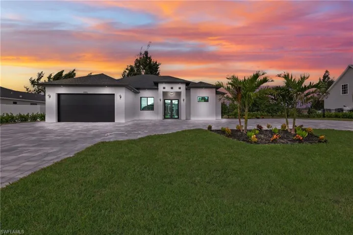 View of front facade featuring decorative driveway, an attached garage, stucco siding, and a front yard