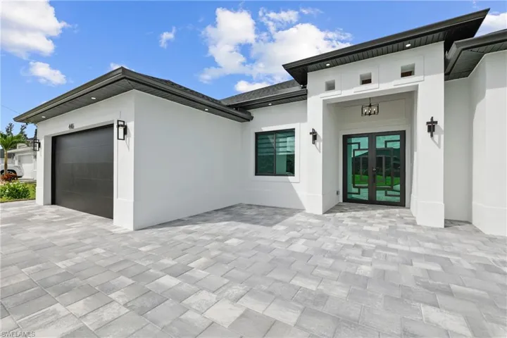 Property entrance featuring an attached garage, stucco siding, decorative driveway, and french doors