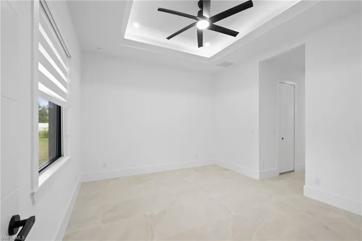 Unfurnished room featuring a raised ceiling and ceiling fan