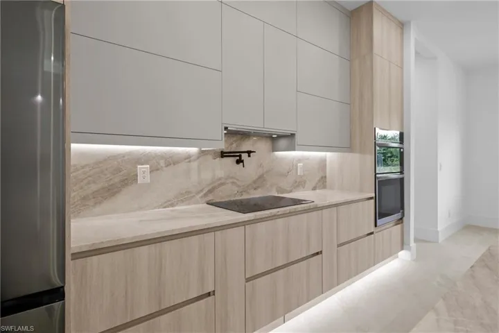 Kitchen featuring light brown cabinetry, appliances with stainless steel finishes, modern cabinets, and light stone counters