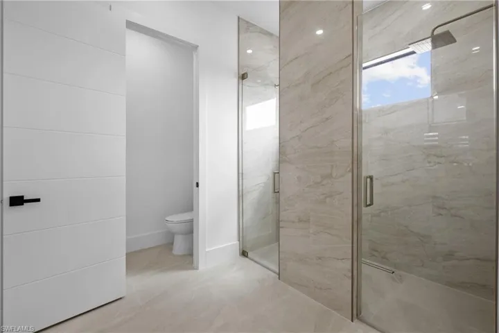 Full bath featuring a marble finish shower and toilet