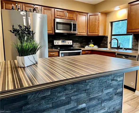 Kitchen featuring sink, light hardwood / wood-style flooring, tasteful backsplash, and appliances with stainless steel finishes