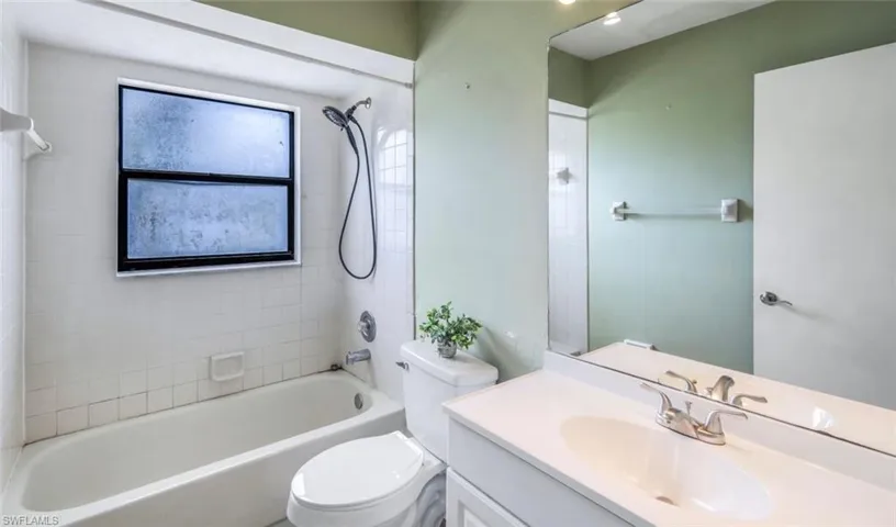 Full bathroom featuring tiled shower / bath combo, vanity, and toilet