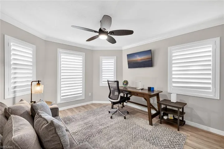 Office area with a ceiling fan, ornamental molding, and light wood finished floors