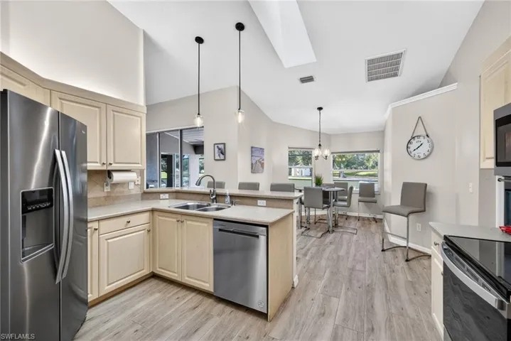 Kitchen with stainless steel appliances, a skylight, lofted ceiling, hanging light fixtures, and a peninsula