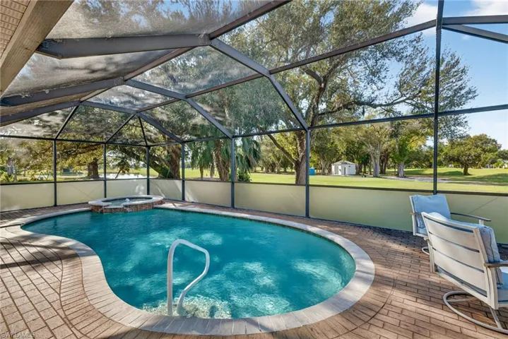 View of swimming pool featuring a sunroom, glass enclosure, and a pool with connected hot tub