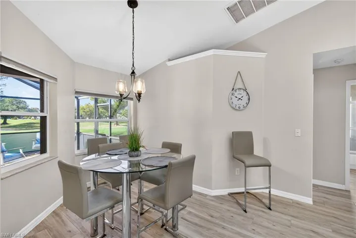Dining area with lofted ceiling, light wood finished floors, a chandelier, and a water view