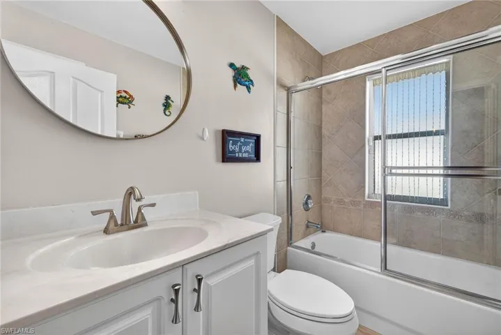 Bathroom with combined bath / shower with glass door and vanity