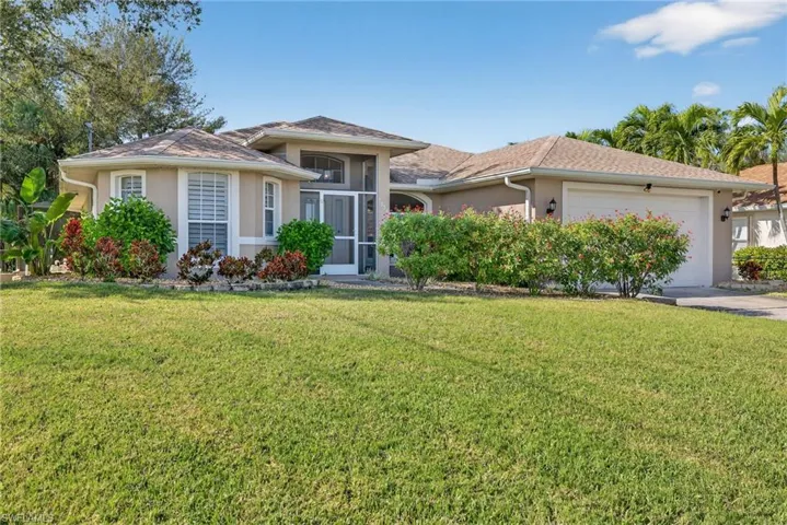 Ranch-style house with stucco siding, a garage, a front lawn, and driveway