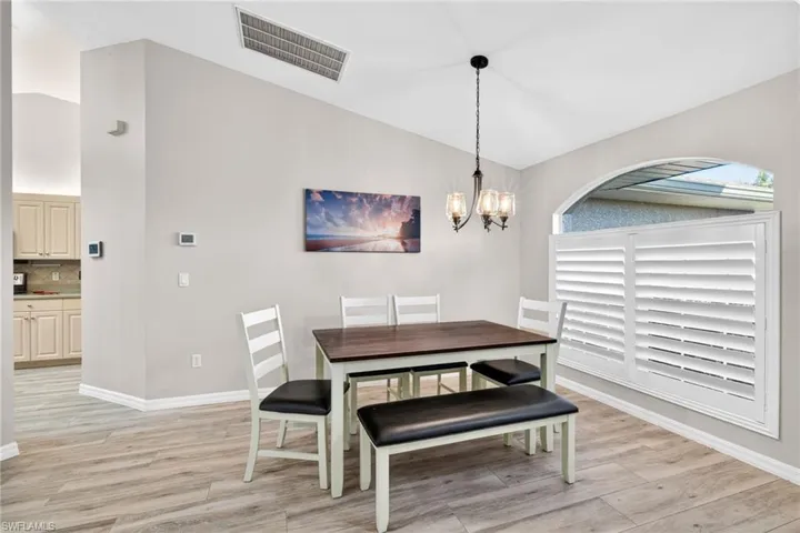 Dining area featuring vaulted ceiling, a chandelier, and light wood-type flooring