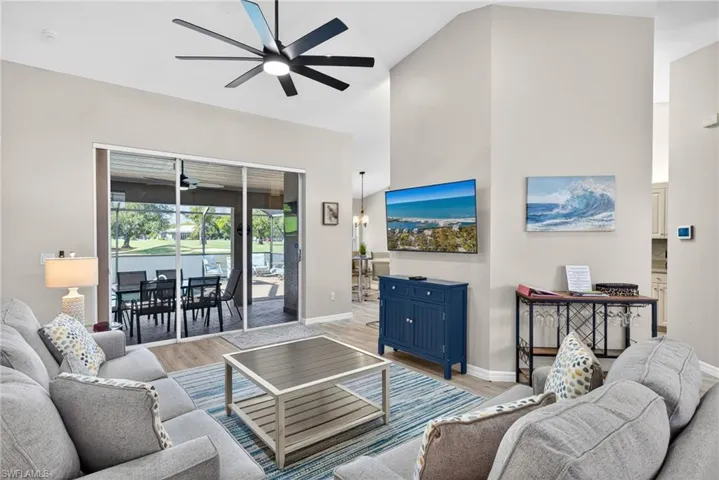 Living room featuring wood finished floors, a high ceiling, a ceiling fan, and a sunroom
