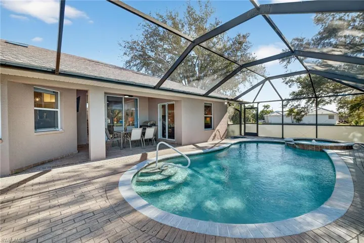View of pool with a sunroom, a patio area, a pool with connected hot tub, a lanai, and outdoor dining space