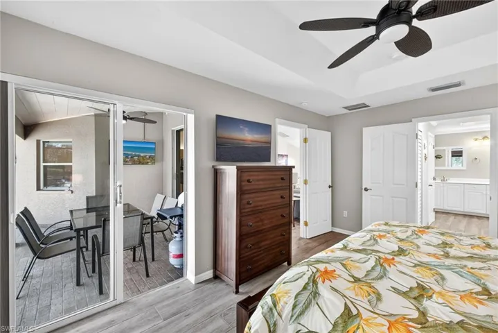 Bedroom with light wood-style floors, ceiling fan, access to exterior, and ensuite bathroom