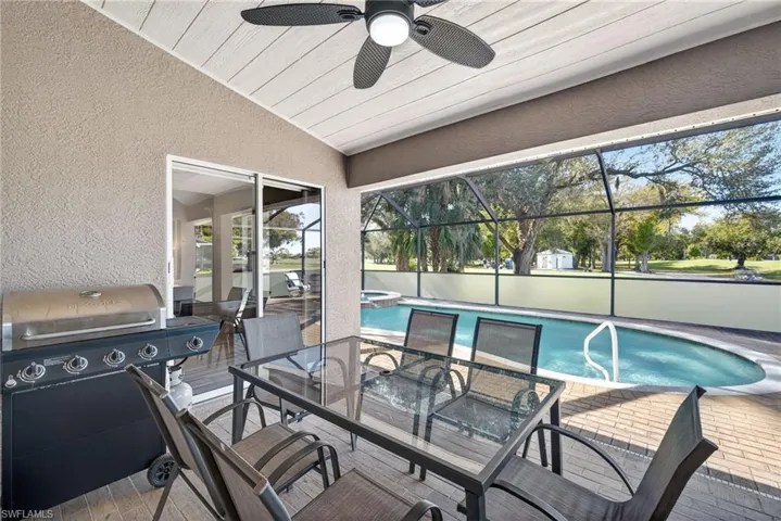 View of patio featuring a grill, glass enclosure, a ceiling fan, outdoor dining space, and a sunroom