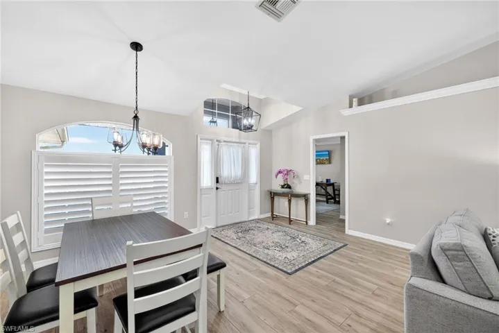 Dining area with a chandelier, light wood finished floors, and high vaulted ceiling