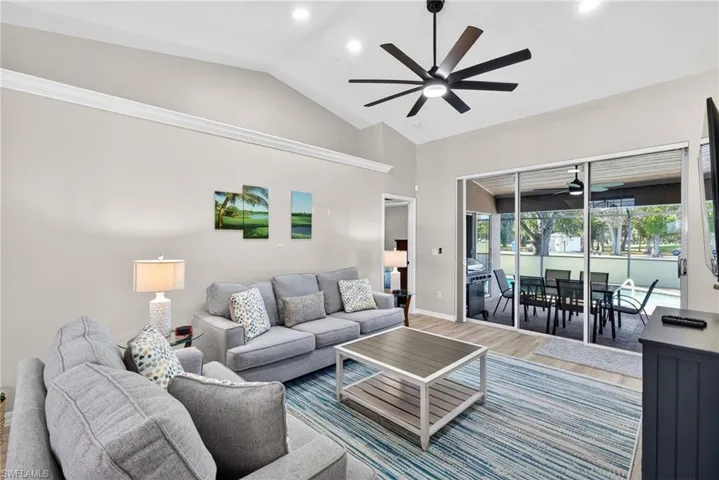 Living room with a sunroom, wood finished floors, vaulted ceiling, recessed lighting, and ceiling fan
