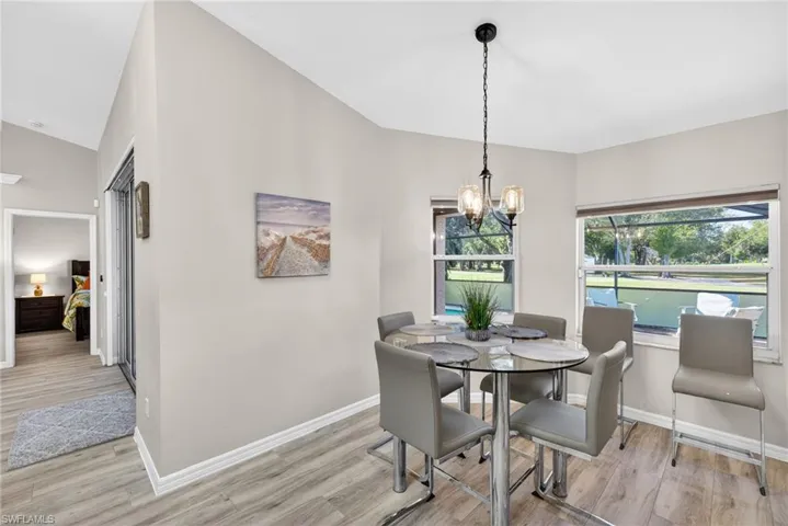 Dining space with light wood-style flooring, lofted ceiling, and a chandelier