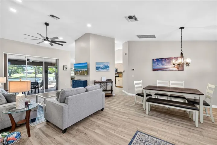 Living room with light wood finished floors, vaulted ceiling, a chandelier, and a ceiling fan