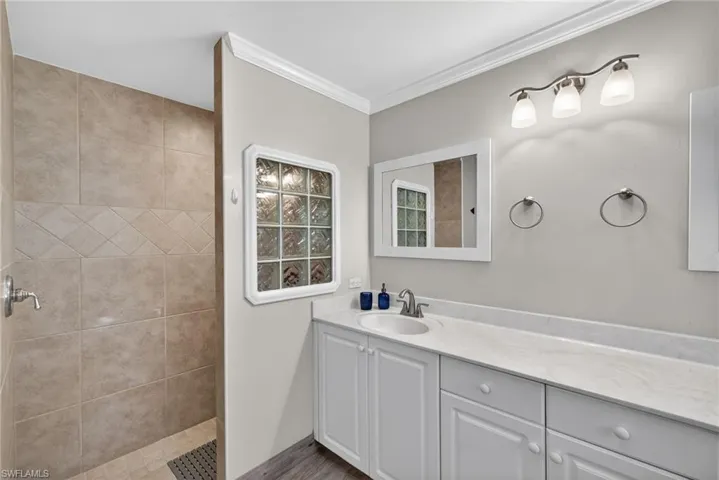 Bathroom featuring vanity, ornamental molding, and a walk in shower