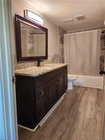 Bathroom featuring vanity, dark wood finished floors, and shower / bathtub combination with curtain