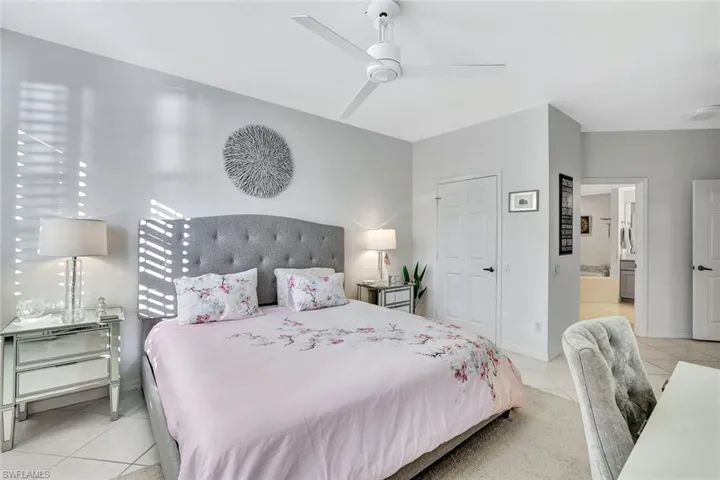 Tiled bedroom featuring ensuite bathroom and ceiling fan