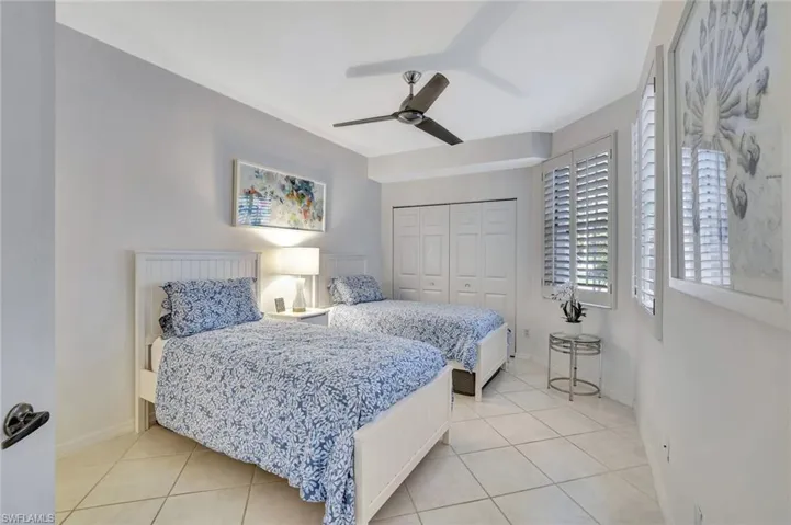 Bedroom with ceiling fan, a closet, and light tile patterned flooring