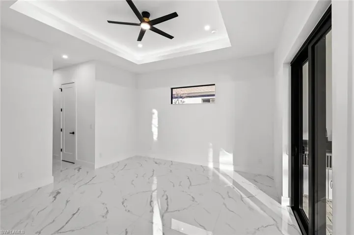 Unfurnished room featuring a raised ceiling and ceiling fan