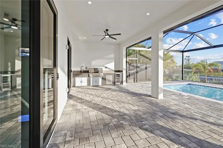View of swimming pool featuring area for grilling, a lanai, ceiling fan, a patio, and a grill