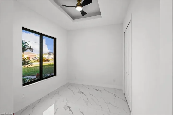 Spare room featuring a tray ceiling and ceiling fan