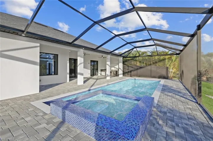 View of pool featuring a lanai, ceiling fan, a patio area, and an in ground hot tub
