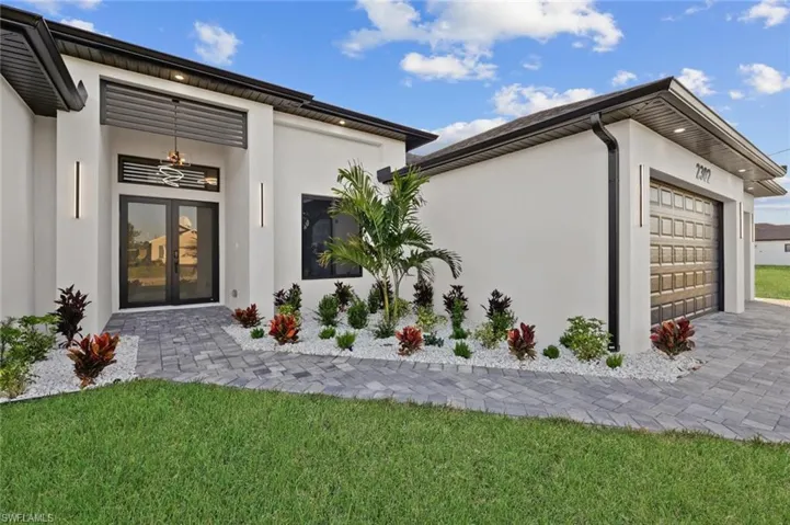 View of exterior entry with a lawn and a garage