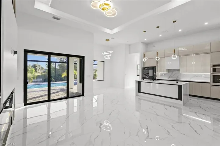 Kitchen with gray cabinetry, a raised ceiling, decorative backsplash, double oven, and decorative light fixtures