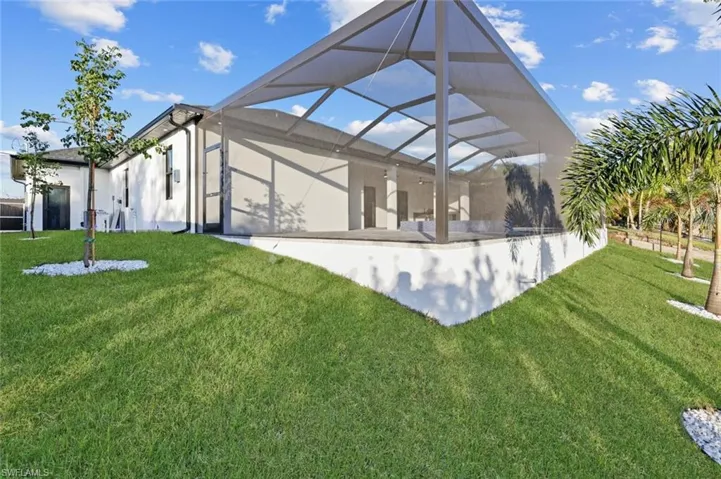 Rear view of property featuring a lanai and a yard