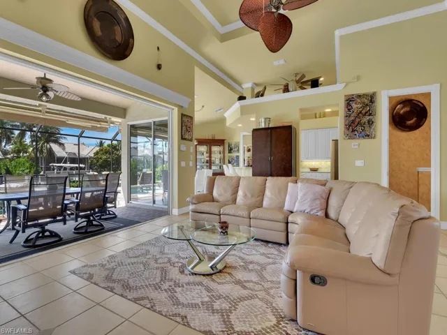 Tiled family room with high vaulted ceiling, ceiling fan, and ornamental molding