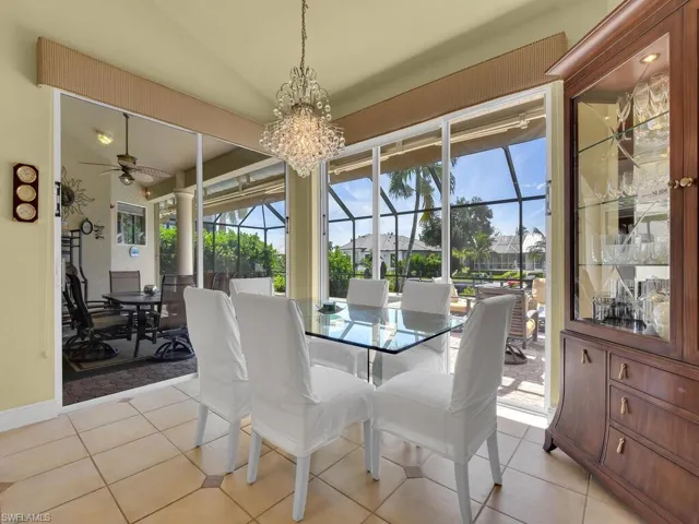 Dining area with ceiling fan with notable chandelier, vaulted ceiling, and light tile patterned floors