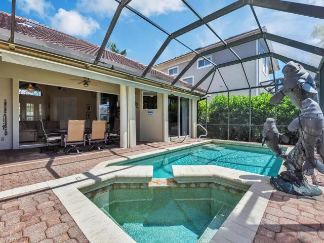View of heated pool featuring glass enclosure, an in ground hot tub, ceiling fan and an awning for late afternoon shade